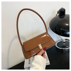 Detail of glossy brown patent leather shoulder bag with elegant golden metallic buckle