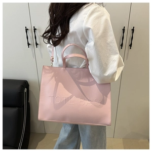 Detailed view of pink leather tote bag with embossed lettering and adjustable shoulder strap