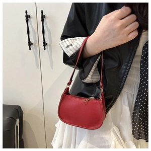 Macro detail of red lychee pattern leather crescent bag with elegant gold hardware