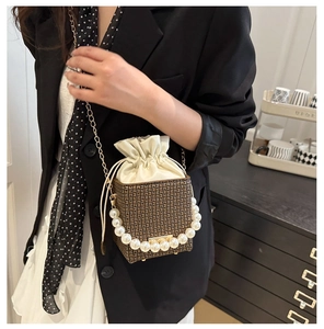Detail of mini bucket bag with pearl handle and chain strap on a model shoulder