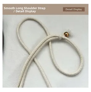 Detail of smooth off-white woven shoulder strap with a decorative golden metal ball charm
