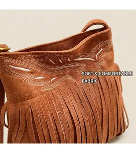Détail d'un sac seau en daim marron avec broderie ondulée blanche et longues franges