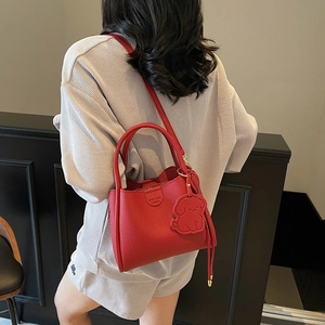 Red pebbled leather bucket bag with dog charm and shoulder strap, crossbody style