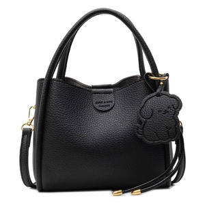 Minimalist black pebble leather handbag with dog charm and crossbody strap