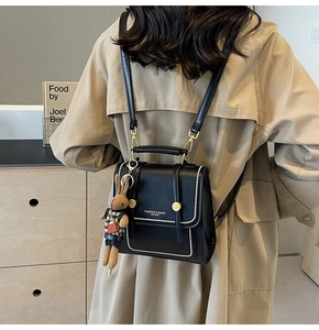 Detalle de mochila vintage de cuero negro con ribete de cuentas y colgante de conejo