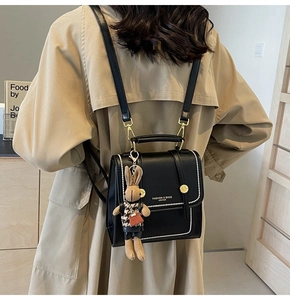 Detalle de mochila de cuero sintético negro con costuras blancas y colgante de conejo