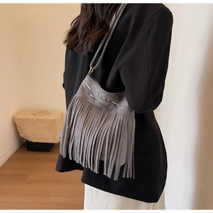 Détail du sac seau en daim gris avec de longues franges et des broderies géométriques