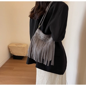 Détail d'un sac seau en daim gris avec broderies et longues franges décoratives