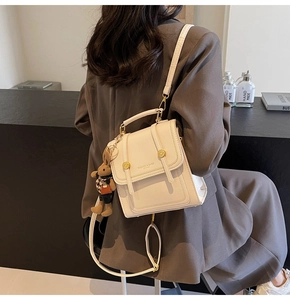 Detalle de mochila de cuero crema con cierre dorado y colgante de conejo marrón