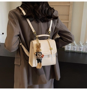 Primer plano de una mochila vintage crema con un colgante de conejo en una modelo