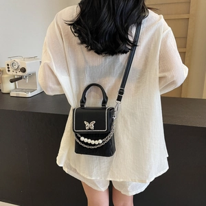 Sac bandoulière en cuir noir chic avec papillon argenté et détail de chaîne perle