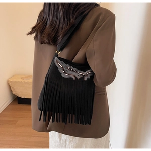 Détail d'un sac seau noir vintage avec broderie délicate et longues franges de décoration