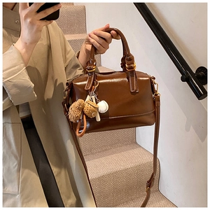 Detail of dark brown glossy Boston bag with cute charms and a detachable shoulder strap