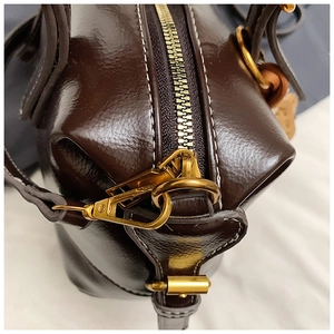 Detail view of vintage dark brown boston bag with high-quality metal hardware and contrast stitching