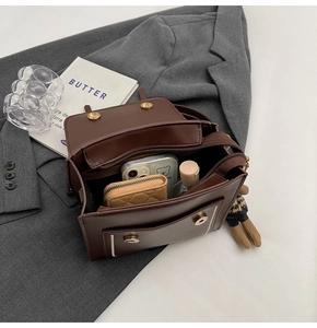 Vista superior del bolso bandolera marrón que muestra el interior espacioso y accesorios
