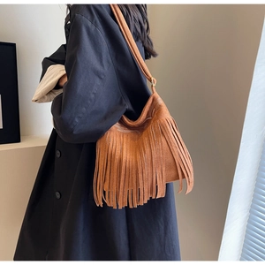 Détail des broderies blanches et longues franges en daim sur le sac bourse marron