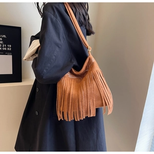 Détail d'un sac seau bohème en daim marron avec de longues franges et des coutures