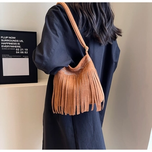 Détail du sac seau en daim marron avec broderies blanches et longues franges déco