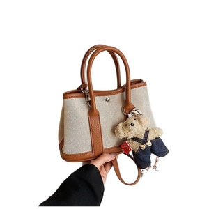 Chic canvas bucket bag with brown leather trim and cute teddy bear plush charm