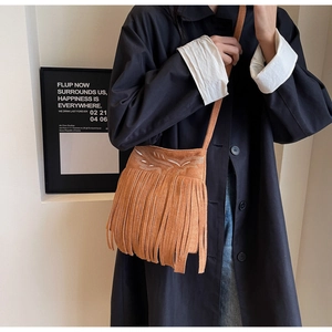 Détail du sac seau en daim marron avec broderie blanche et longues franges pendantes