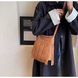 Détail du sac seau en daim marron avec broderie blanche et longues franges de glands