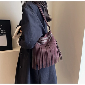Détail du sac seau en daim avec broderie ethnique et longues franges à glands