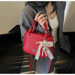 Detail of red lychee pattern bucket bag with lace bow and silver heart pendant