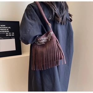 Détail du sac seau en daim marron foncé avec de longues franges et des broderies