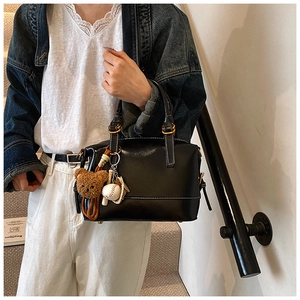 Detail of glossy black Boston handbag with white contrast stitching and cute charms