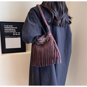 Détail du sac seau en daim bordeaux avec de longues franges et coutures bohèmes