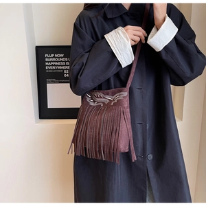 Détail du sac seau en daim marron foncé avec broderies ethniques et longues franges