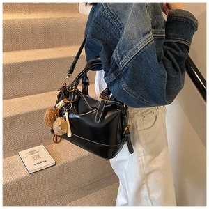 Detailed view of black leather Boston bag with white stitching and gold hardware details