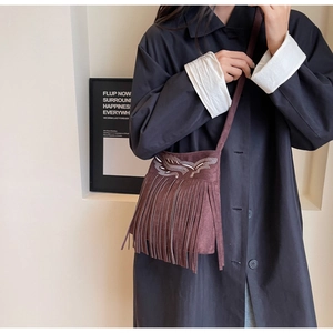 Détail du sac seau en daim marron avec longues franges et broderie bohème