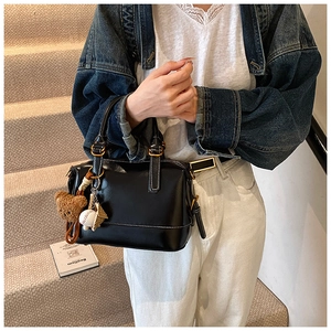 Detail of black Boston bag featuring white contrast stitching and trendy charms