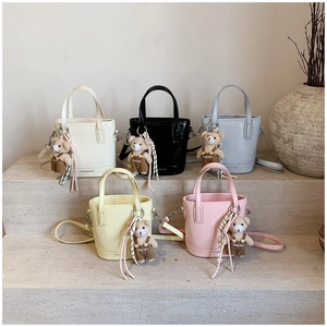 Detailed display of fashion bucket bags in five colors with cute bear charms on stone steps