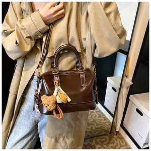 Detail of vintage brown oil wax leather Boston bag with a cute bear charm pendant