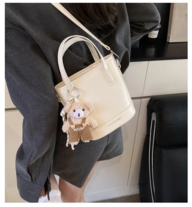 Close-up of cream bucket bag with cute bear charm and adjustable shoulder strap