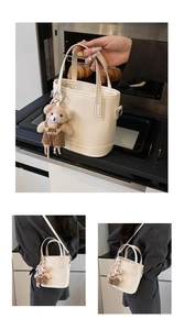Close-up of cream bucket bag with cute bear charm and adjustable shoulder strap