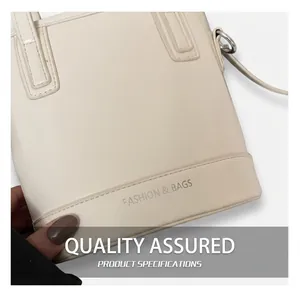 Detail showing the cream white bucket bag with elegant metal loops and logo engraving