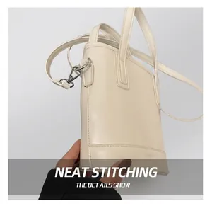 Detail of white PU leather bucket bag with silver metal buckles and fine stitching