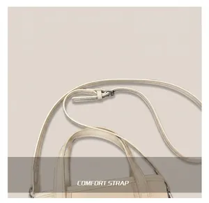 Detail of adjustable cream white shoulder strap with silver metal buckle on bucket bag