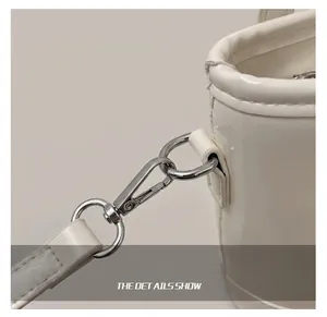 Detailed close-up of glossy white leather shoulder bag with silver metal swivel hooks