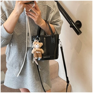 Mirror selfie showing a black shiny bucket bag with bear charm and fashion lettering