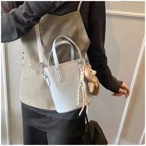 Detail of light blue bucket bag with adjustable strap and cute brown bear charm accessory