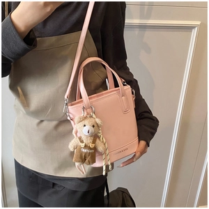 Detail of pink faux leather bucket bag with cute bear charm and fashion logo print