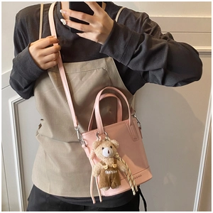 Pink leather bucket bag with a cute teddy bear charm and adjustable shoulder strap