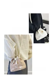 Detail of woven straw bucket bag featuring floral embroidery and pearl drawstring