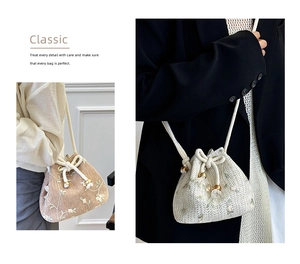 Detailed macro view of white flower embroidery and natural straw texture on bucket bag
