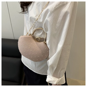 Pink heart-shaped mini bag with sparkling texture and golden handle worn by a model