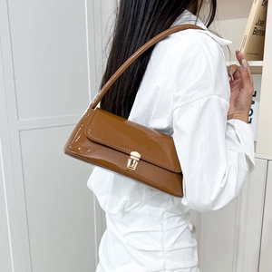 Minimalist caramel patent leather underarm baguette bag with glossy finish and gold clasp
